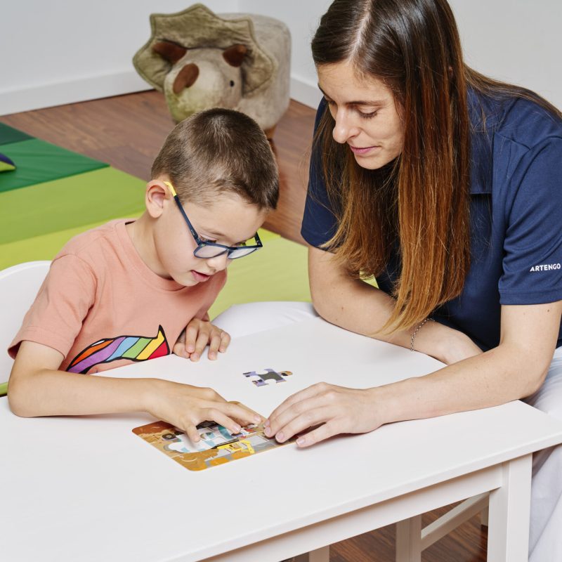 terapeuta ayudando a niño a armar un puzzle